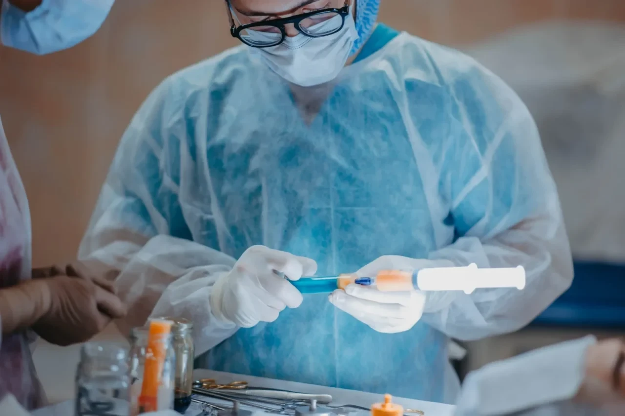 Chirurg im OP-Saal zieht Spritze mit Lipofilling auf