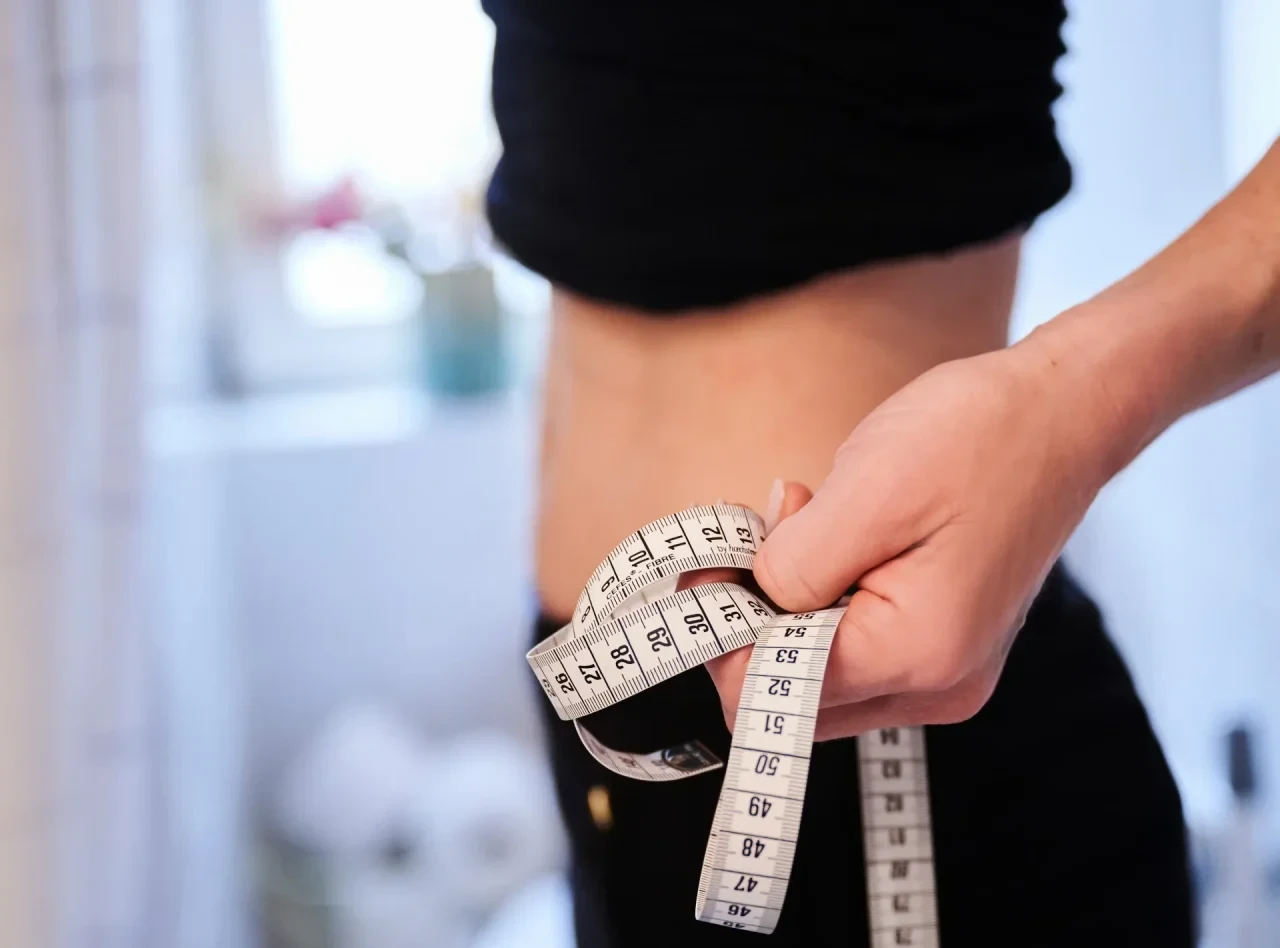 Schlankes Mädchen hält Maßband um die Taille