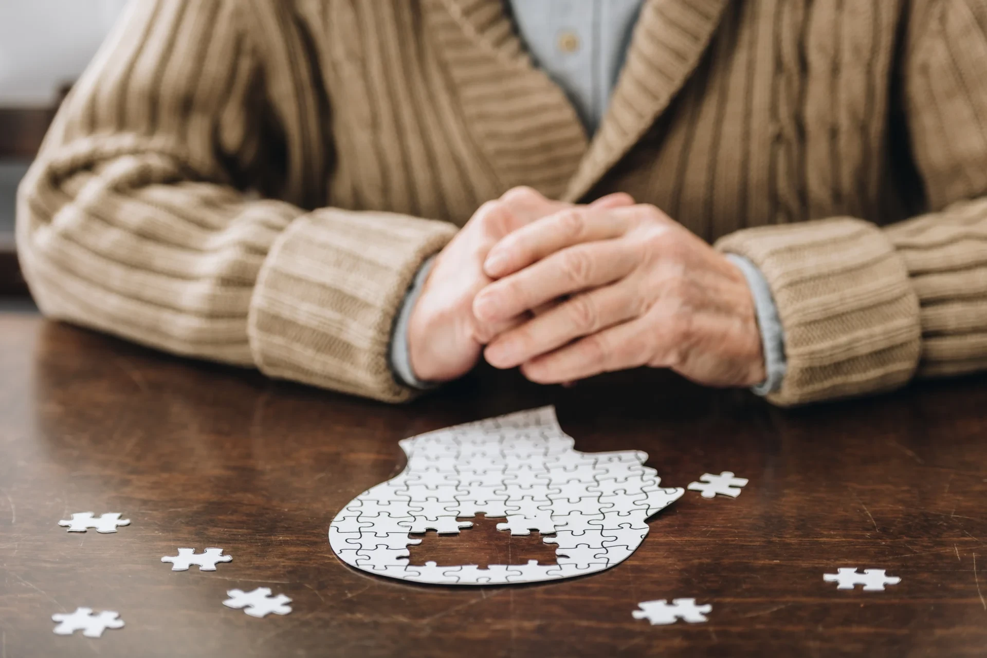 Alter Mensch vor einem Puzzle in Kopfform, dem ein paar Teile fehlen