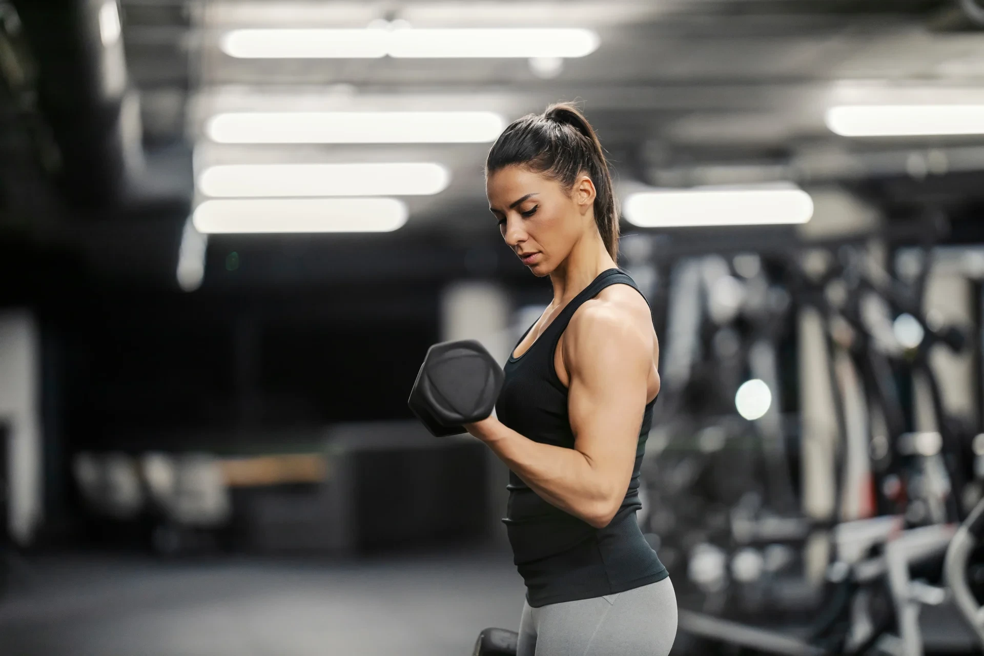 Sportliche Frau trainiert ihren Bizeps im Fitnessstudio