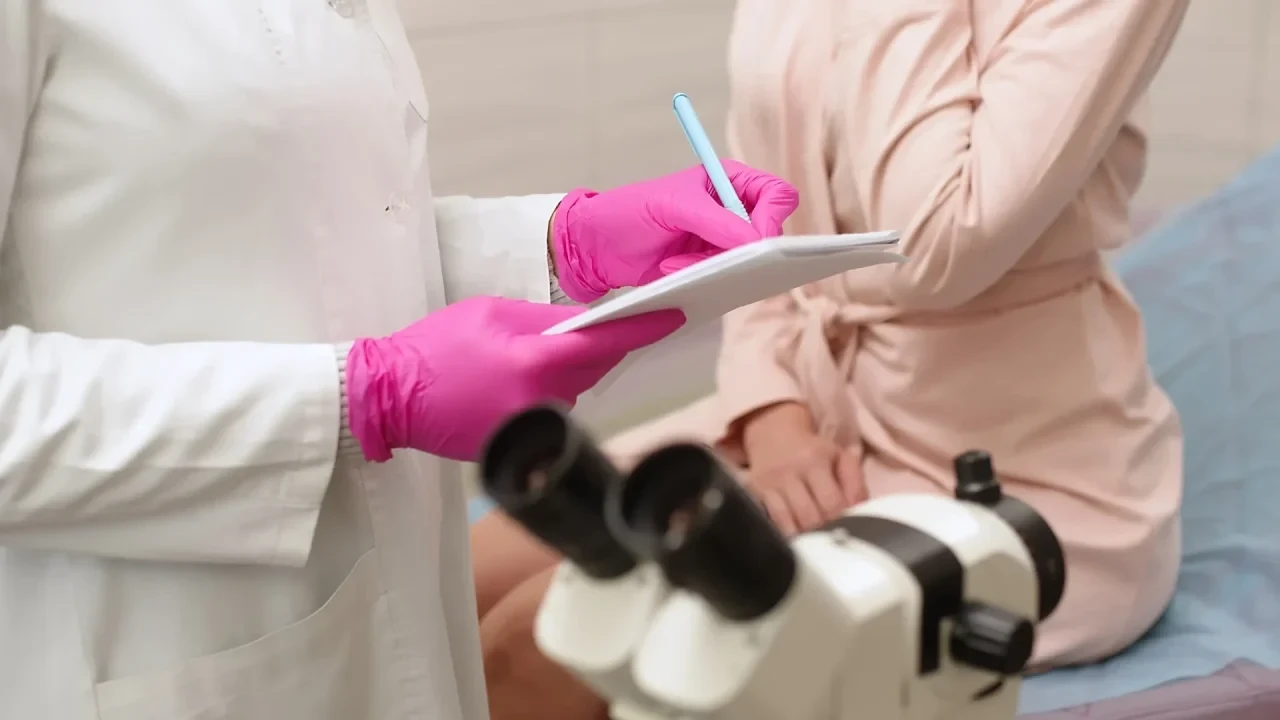 Ärztin in Schutzhandschuhen dokumentiert Befunde während einer gynäkologischen Untersuchung – regelmäßige Tests auf sexuell übertragbare Infektionen können schwere Folgen verhindern.