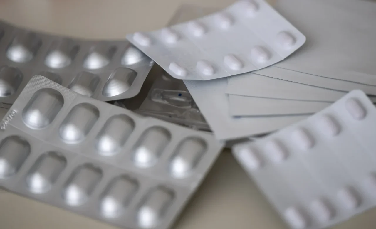 Medikamente verschiedener Hersteller in Form von Tabletten und Pflastern liegen in einer Apotheke auf dem Tisch.
