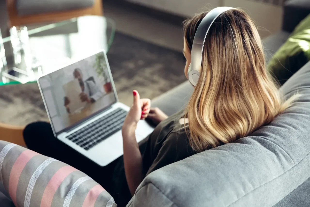 Junge Frau mit Kopfhörern bei einer Videositzung am Laptop