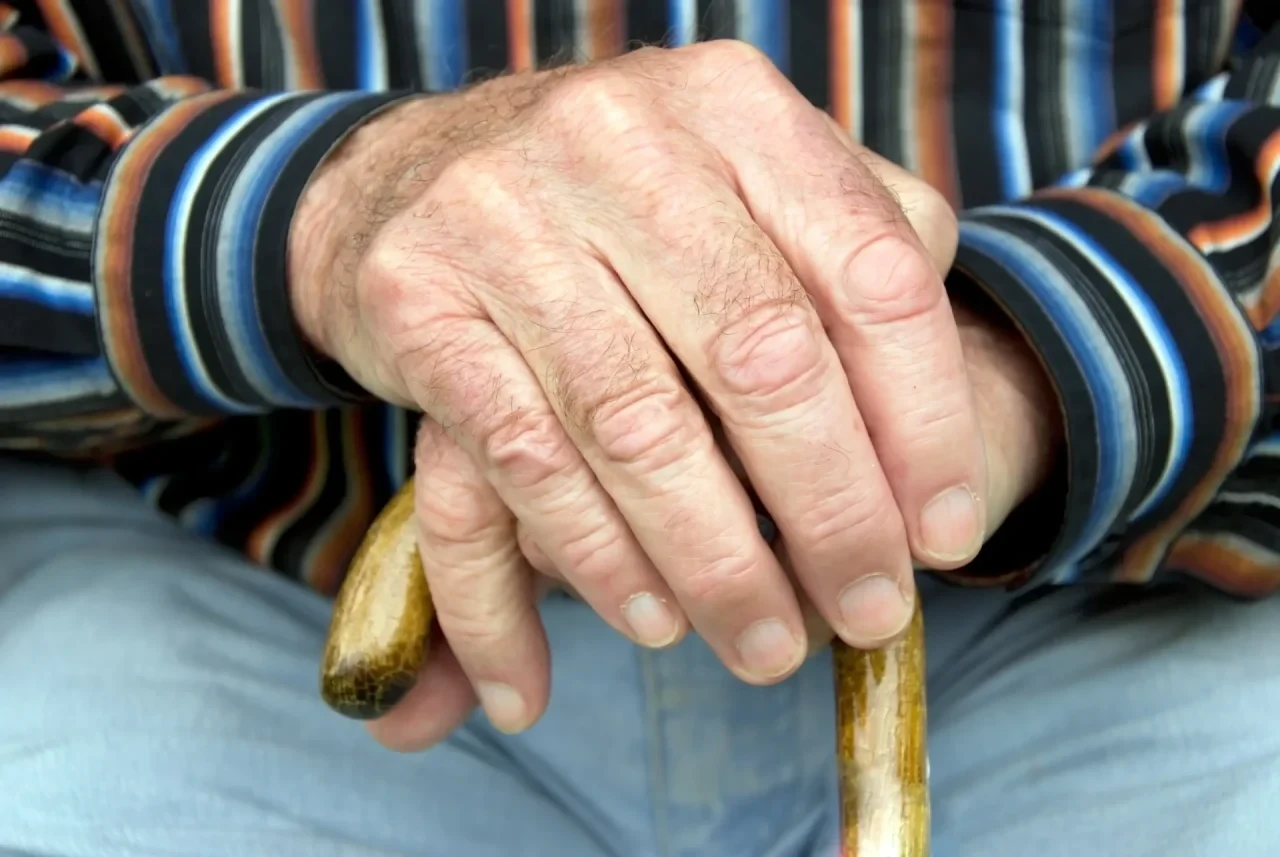 Faltige Hand eines alten Mannes auf einem Gehstock