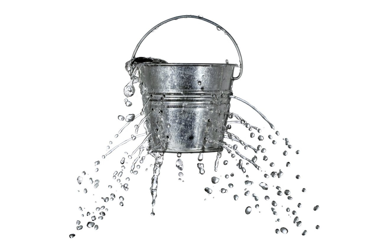 Ein Metalleimer mit zahlreichen Löchern, aus denen Wasser in alle Richtungen herausspritzt