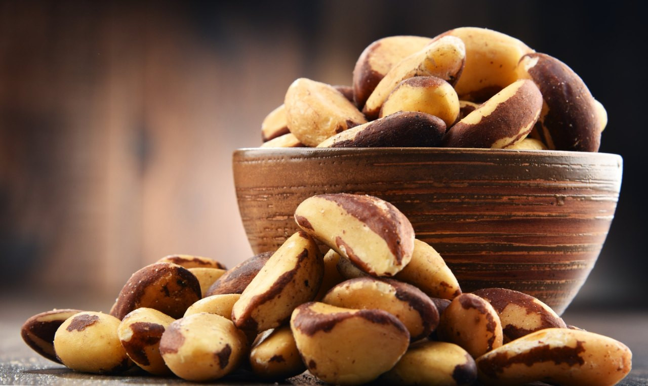 Bowl with Brazil nuts on wooden table. Delicacies