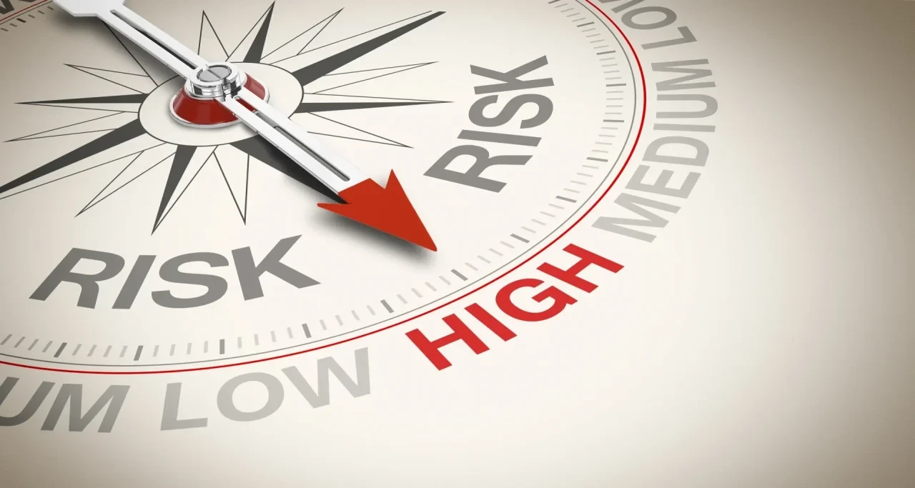 Nahaufnahme eines Messinstruments mit Zeiger, der zwischen den Bereichen „Low Risk“ und „High Risk“ steht,