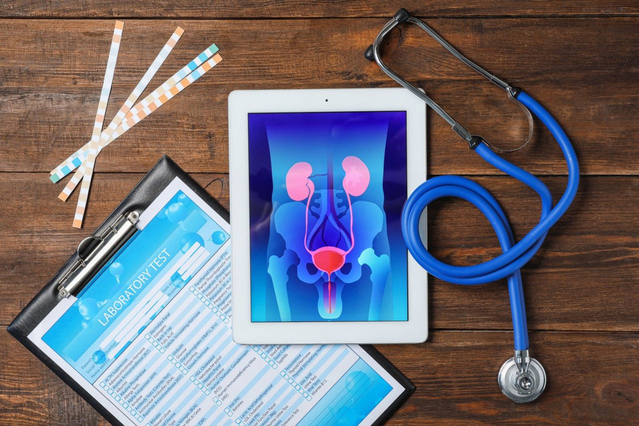 Auf einem Holztisch liegen ein Tablet mit einer grafischen Darstellung der menschlichen Prostata, medizinische Fragebögen, Wattestäbchen und ein Stethoskop