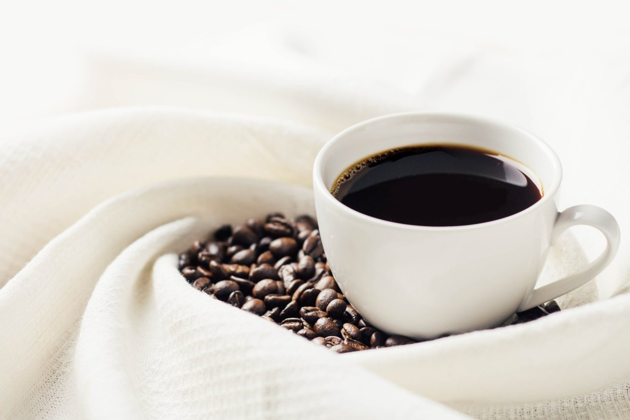 eine Tasse schwarzer Kaffee und Kaffeebohnen