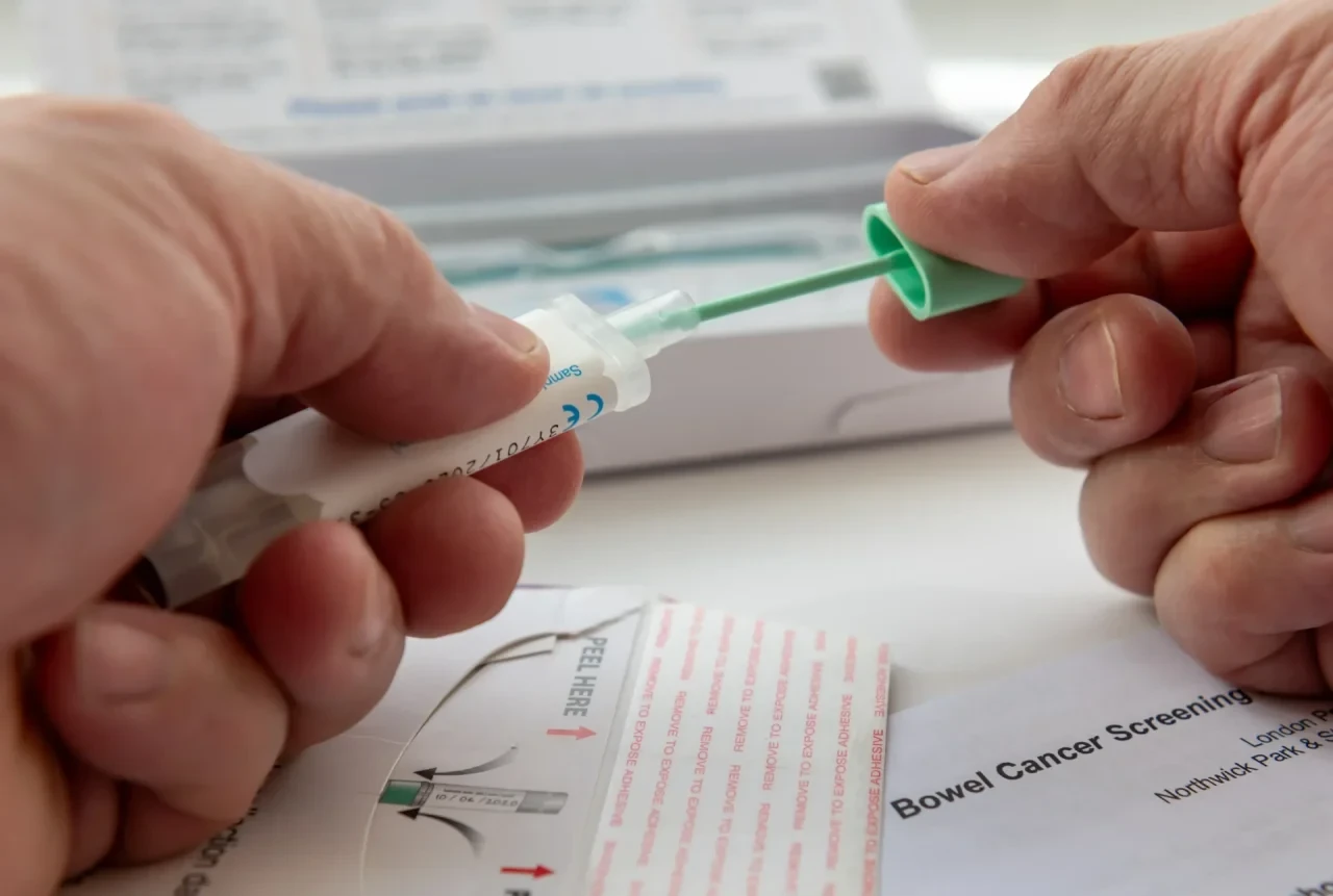 Person legt eine Probe für einen FIT-Stuhltest in einen Behälter, um sie per Post zur Untersuchung einzusenden.