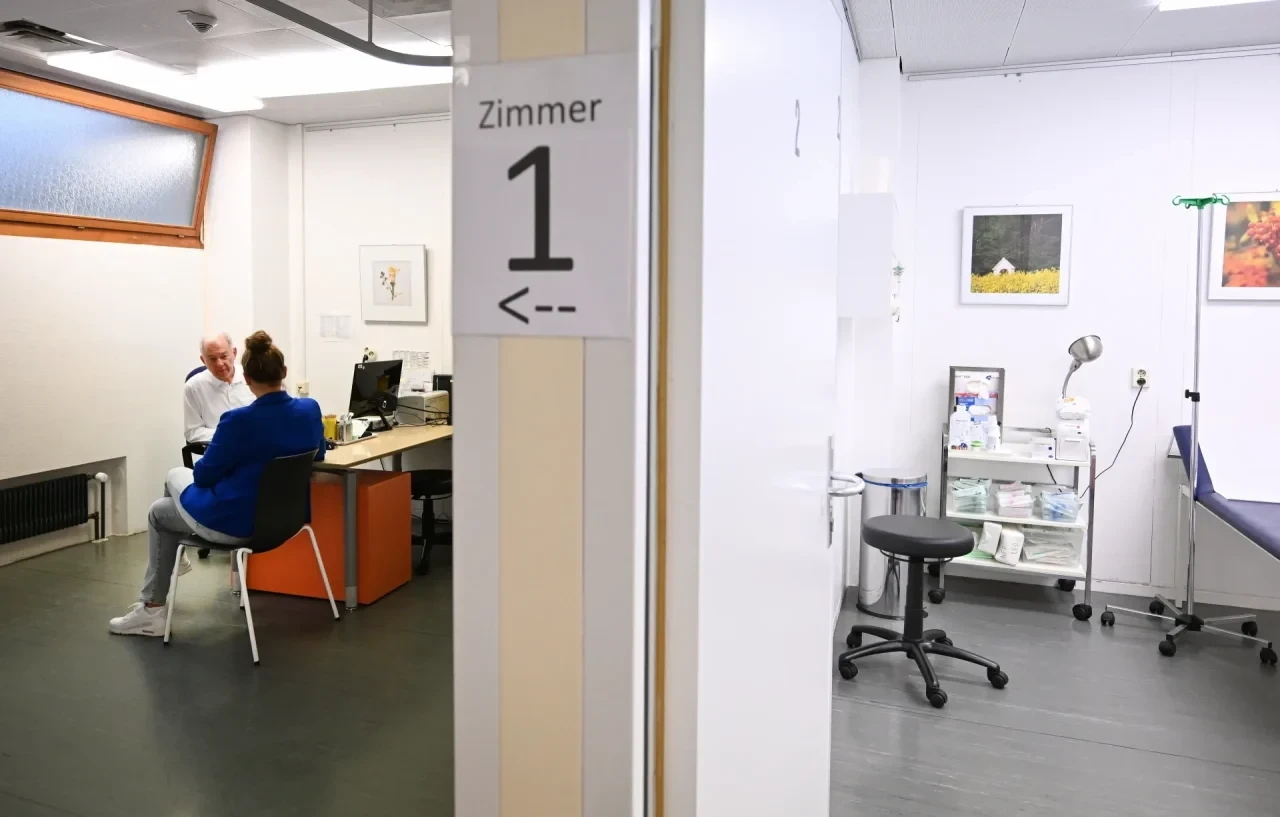 Ein Arzt spricht in einer Bereitschaftspraxis in einem Krankenhaus in einem Untersuchungsraum mit einer Patientin (gestellte Szene