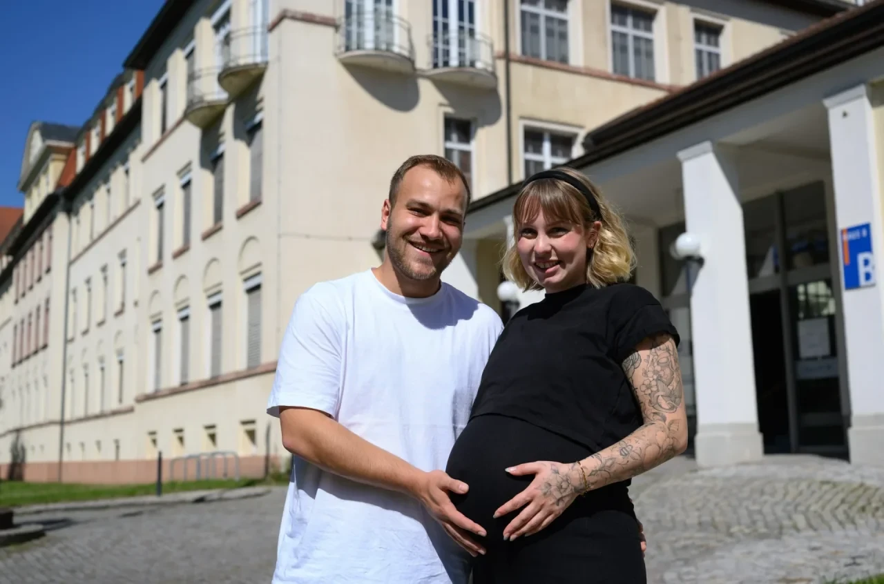 Louise Ammon und ihr Mann Tom stehen gemeinsam vor der Frauenklinik in Chemnitz.