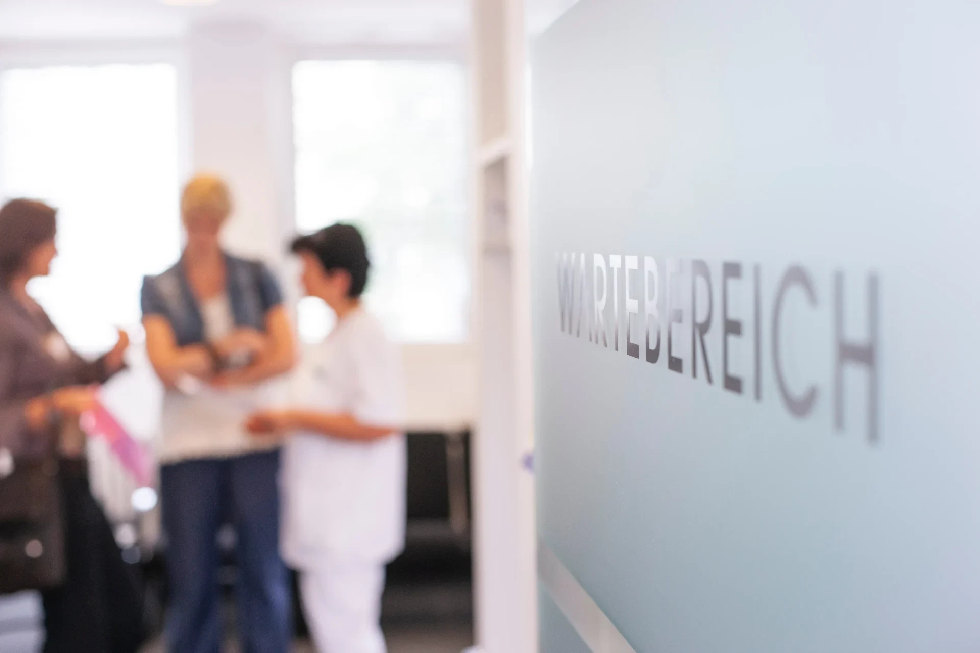 Wartebereich mit Patientinnen und Ärztin im Hintergrund
