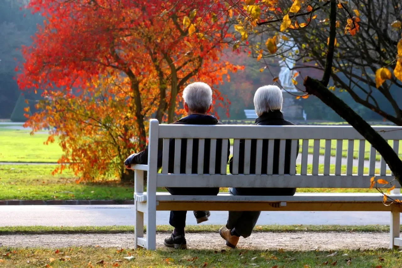 Älteres Paar auf einer Parkbank, herbstliche Stimmung