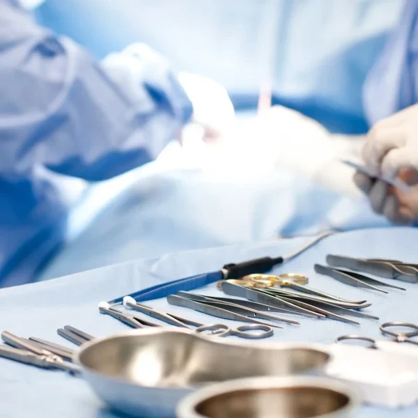 Chirurgisches Team während eines operativen Eingriffs im Operationssaal; im Vordergrund liegen sterile OP-Instrumente auf einem Instrumententisch.