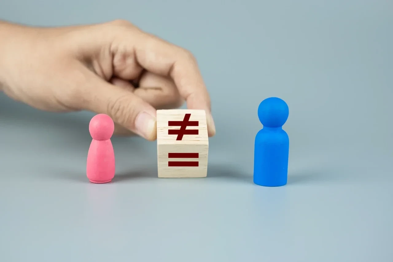 Hand platziert Würfel mit Ungleichheitszeichen zwischen rosa und blauer Spielfigur