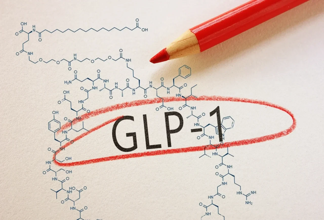 Chemische Strukturformel von Semaglutid auf hellem Papier, auf der die Abkürzung „GLP-1“ mit einem roten Holzfarbstift kreisförmig markiert ist. Darüber der Schriftzu g GLP-1