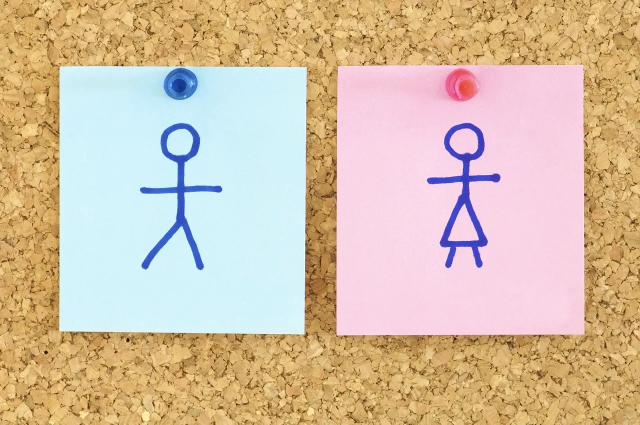 Papier-Silhouetten von Mann und Frau auf einer Korkwand.