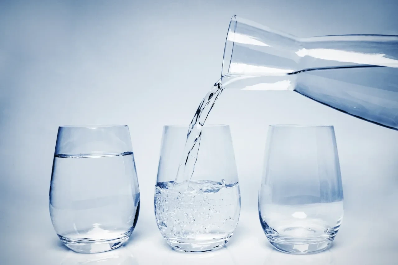 Wasser wird aus Karaffe in Wassergläser gegossen