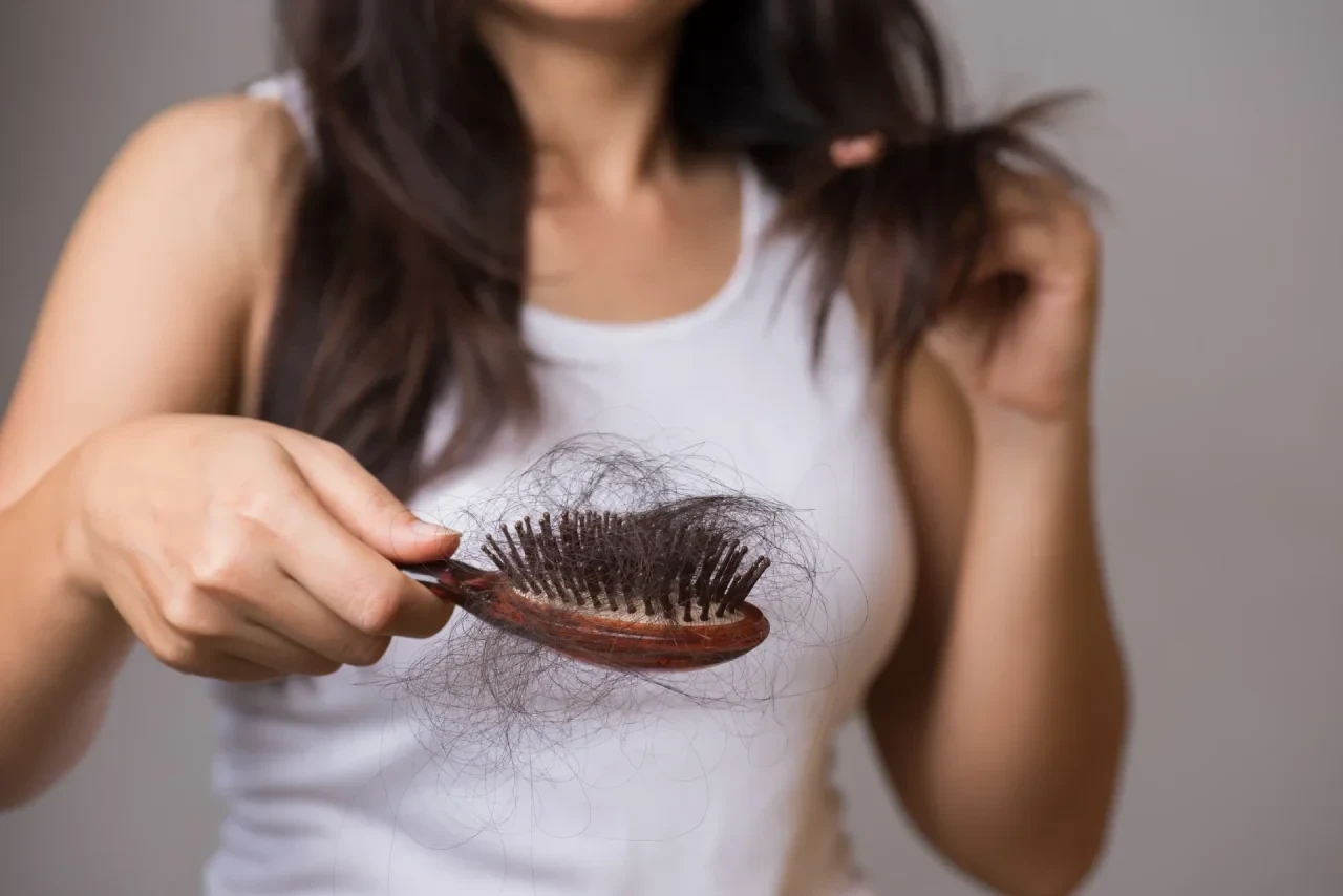 Frau mit Haarbürste in der viele ausgefallene Haare zu sehen sind