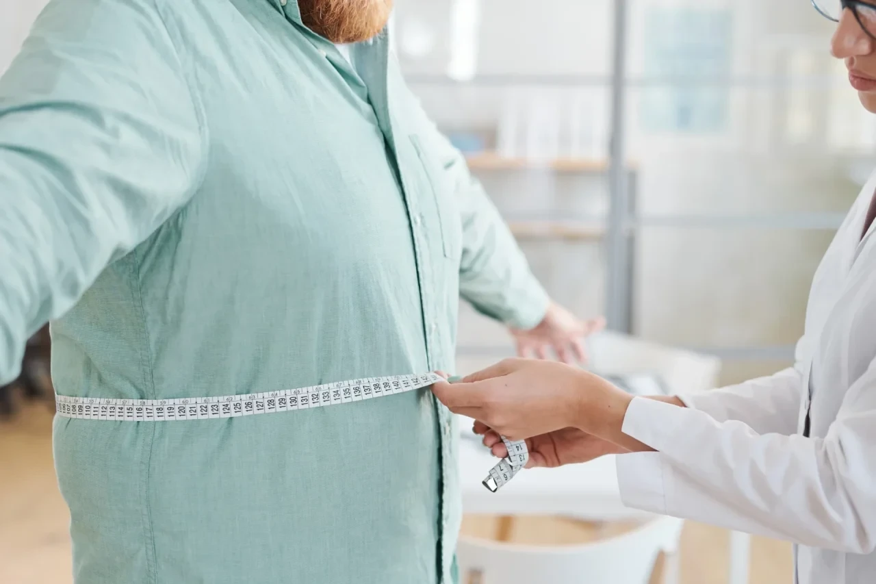 Ärztin misst Bauchumfang eines Patienten mit Adipositas