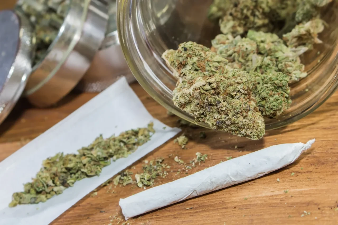 Cannabisblüten und ein gedrehter Joint auf einer Holzoberfläche