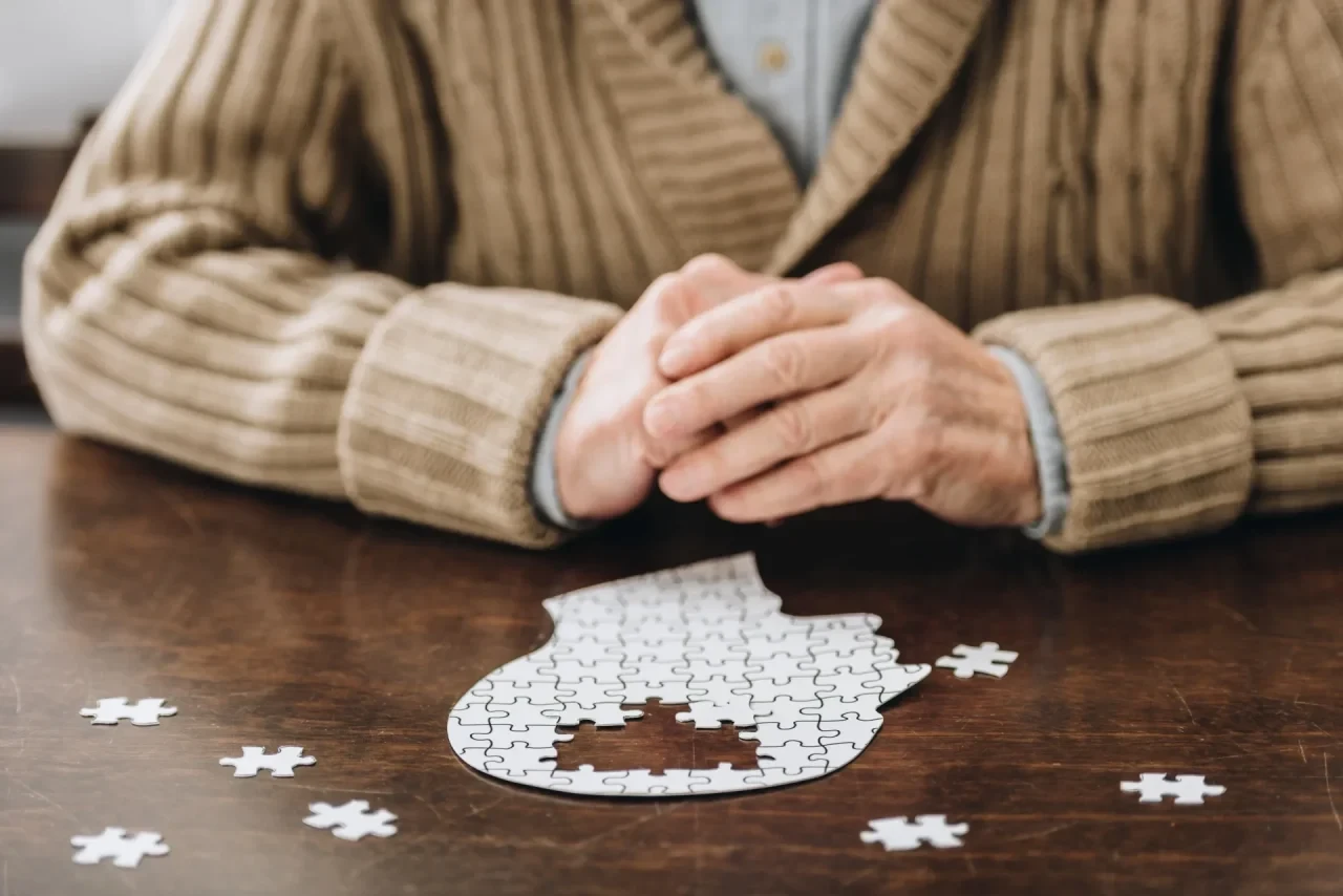 Ein älterer Mann sictz vor einem Puzzle - ein Kopf in dem noch einige Puzzlestücke fehelen
