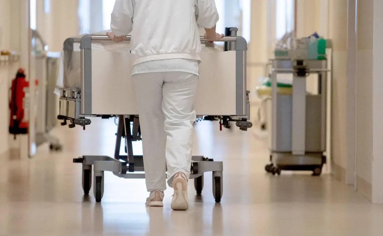 Krankenpflegerin schiebt Bett über Krankenhausflur