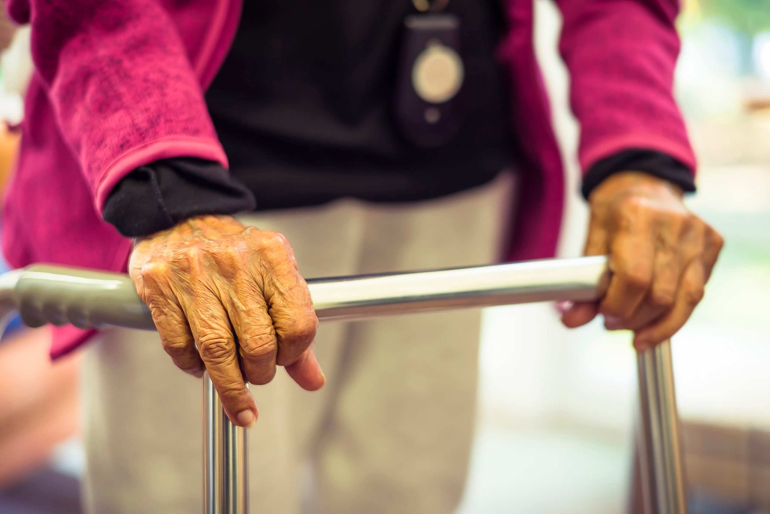 Ältere Frau läuft mit einem Rollator. Zu sehen sind ihre Hände am Griff.