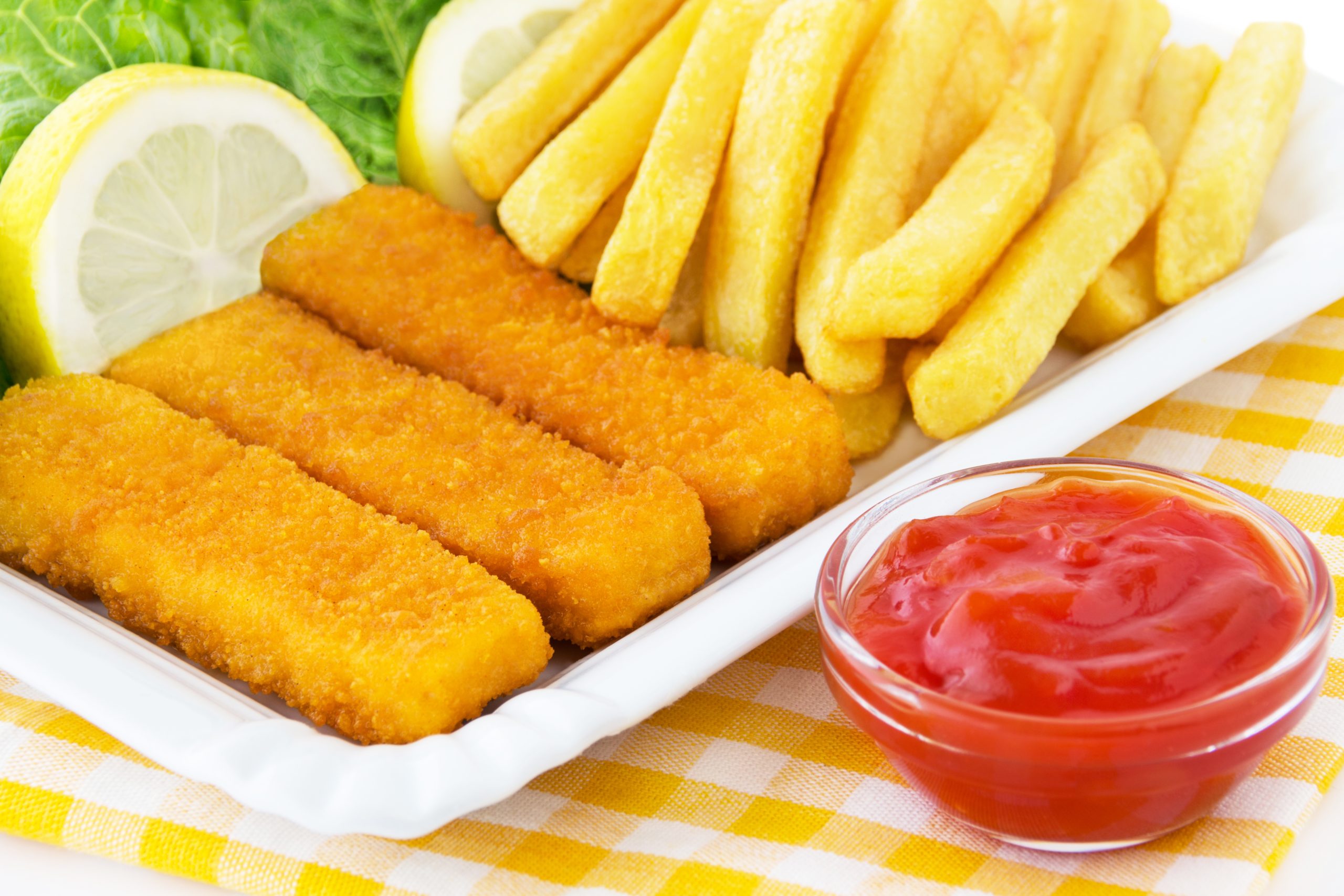 Teller mit Fischstäbchen, Pommes, Ketchup und Zitrone
