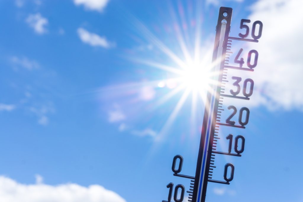 Thermometer vor Himmel mit Wolken im Hintergrund.