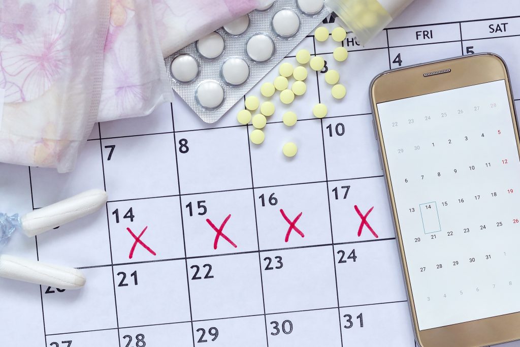 Angekreuzte Kalendertage mit Tampons und Pillen