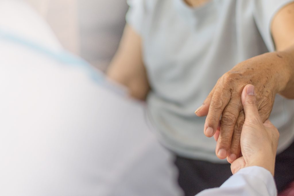 Arzt untersucht Hand einer älteren Patientin.