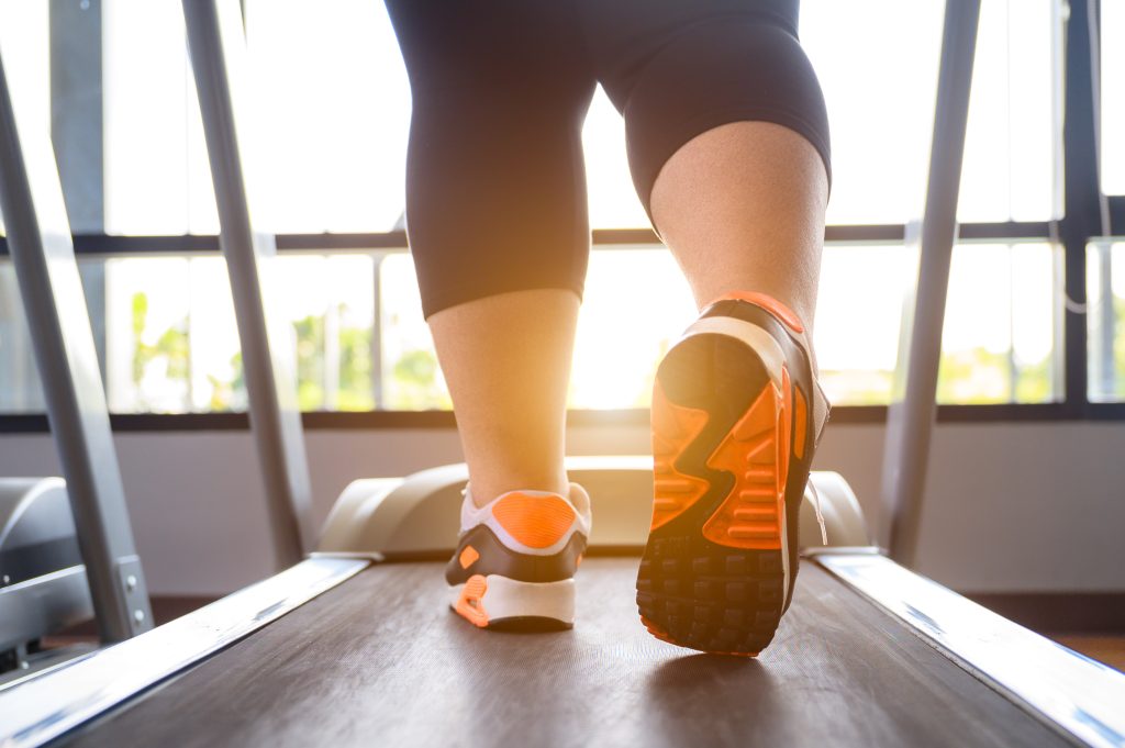 Frauenfüße in Joggingschuhen auf Laufband