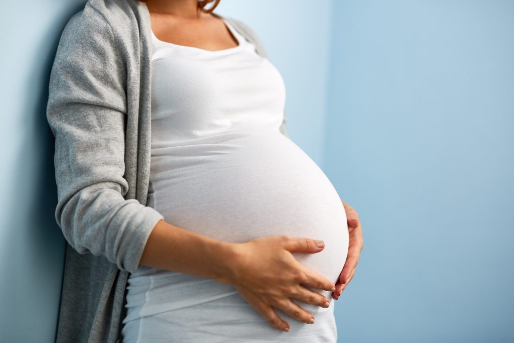 Schwangere Frau die ihren Bauch anfasst