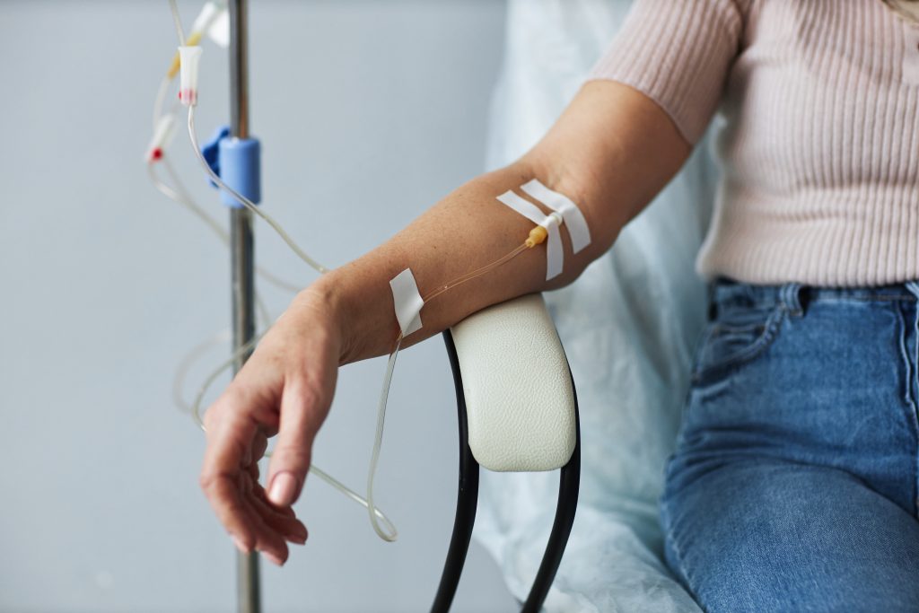 Closeup of female hand with IV drip infusion in treatment session at hospital
