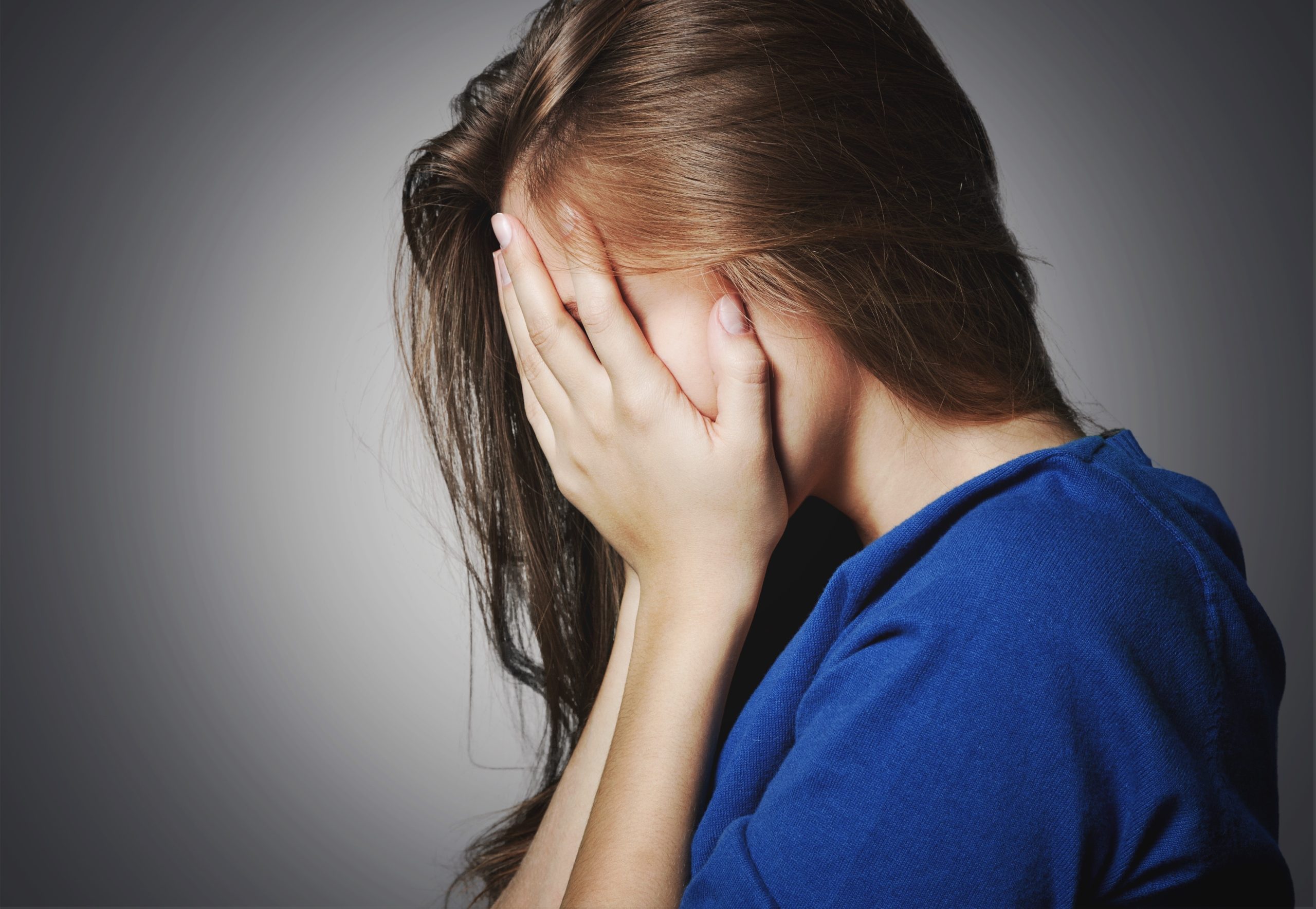 Traurige Frau hebt Hände übers Gesicht