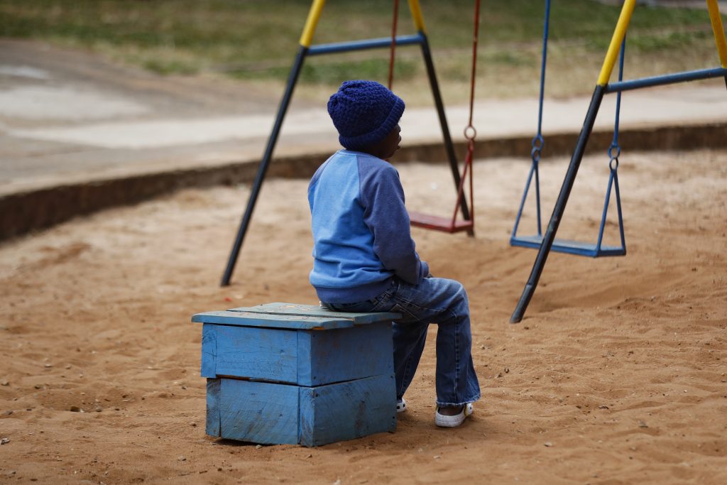 Ein Kind sitzt vor einem Klassenzimmer im Nyumbani Children's Home.