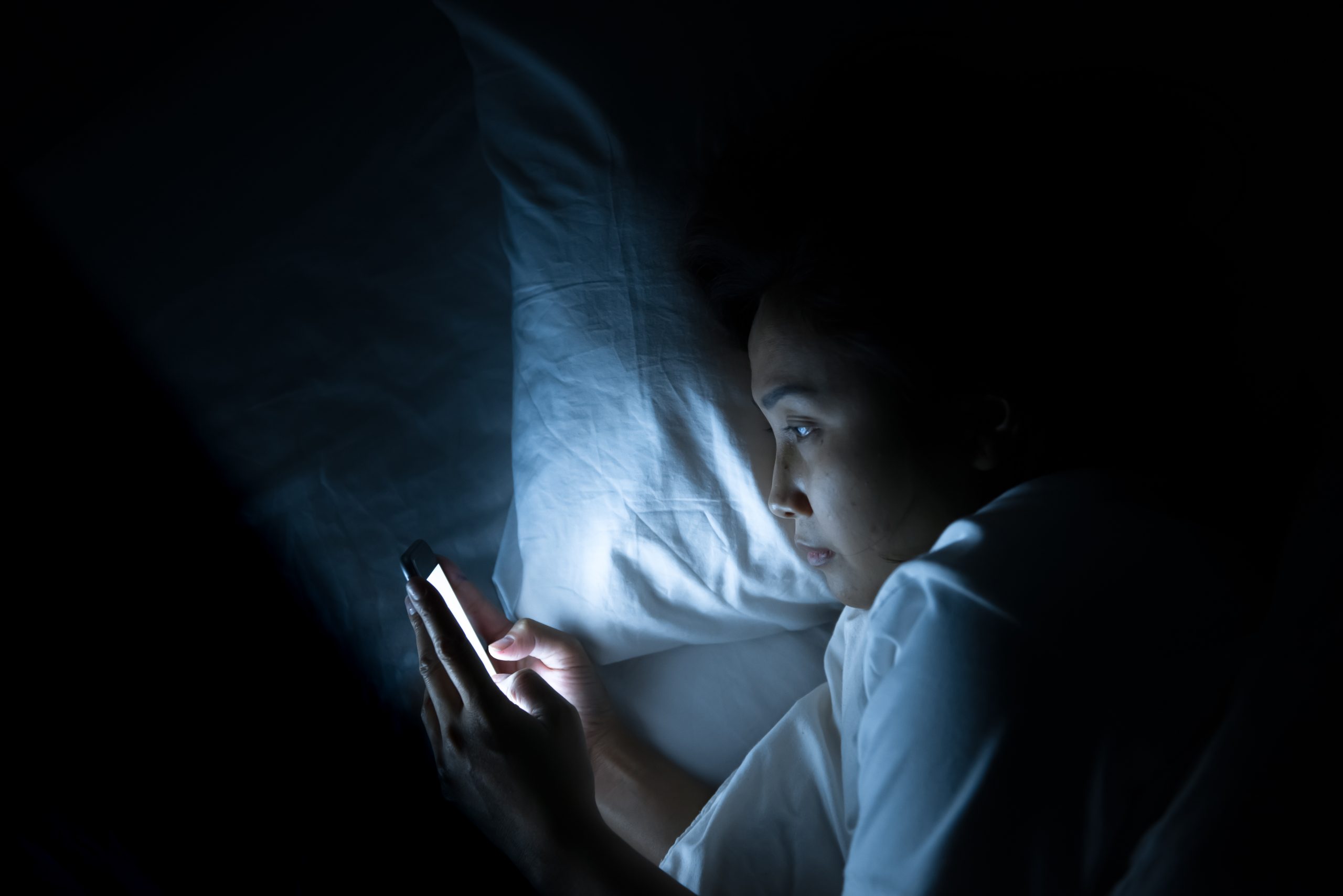 Asian woman play smartphone in the bed at night,